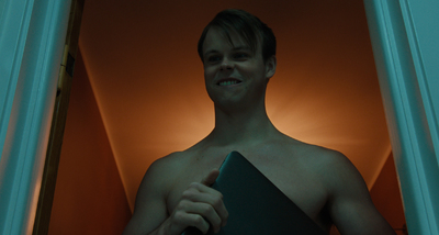 a shirtless man holding a folder in a doorway