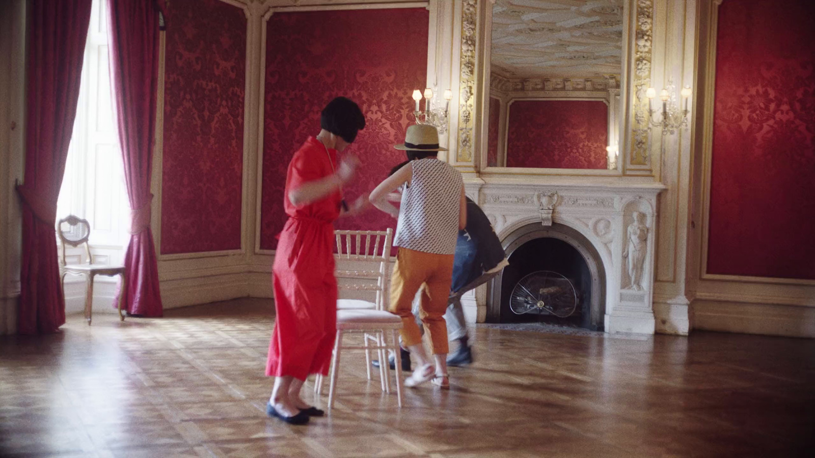 a woman in a red dress standing next to a chair