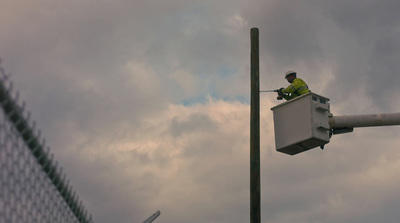 a man in a yellow shirt is working on a street light