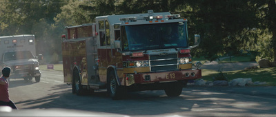 a fire truck driving down a street next to a forest