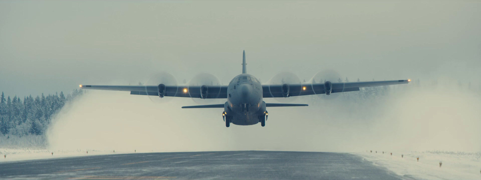 a large jet flying over a snow covered runway