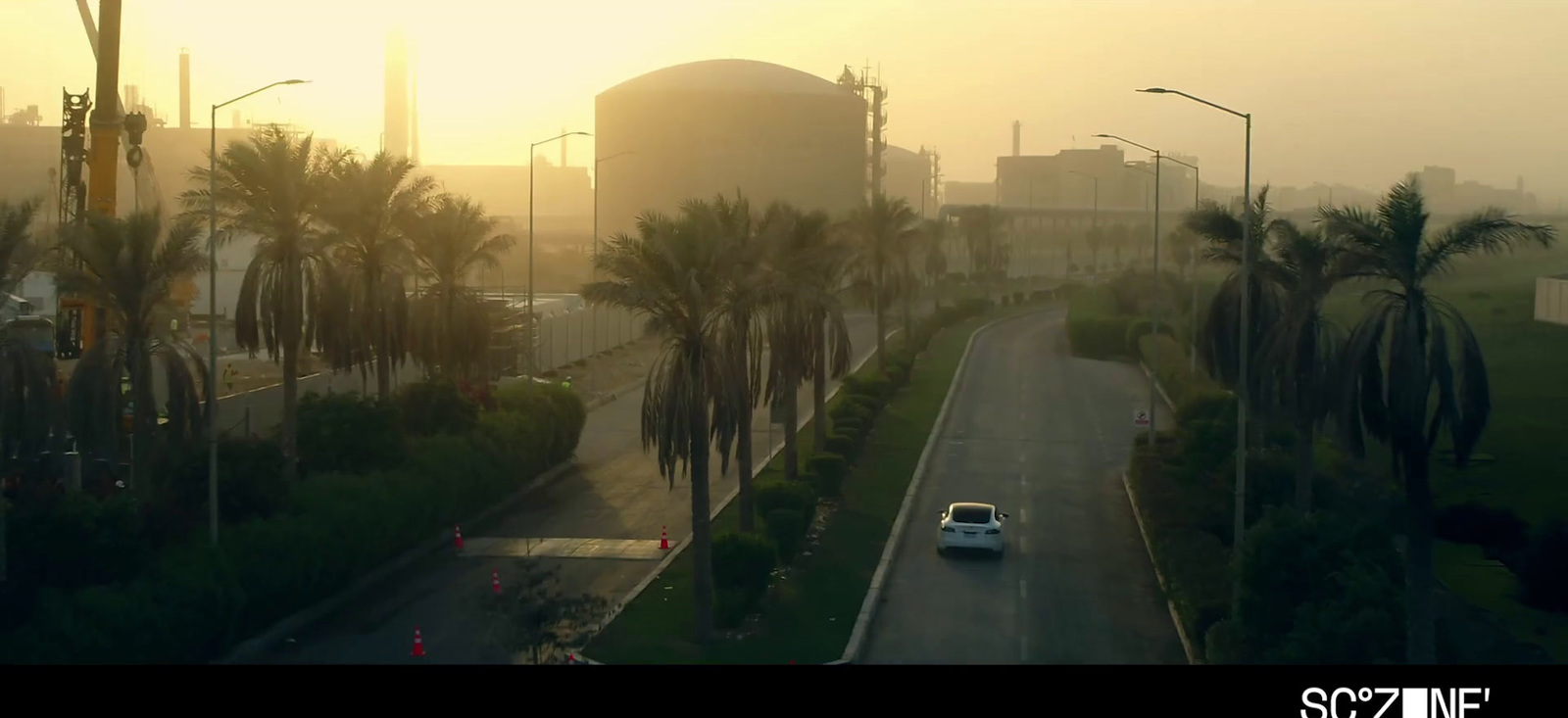 a car driving down a street next to palm trees