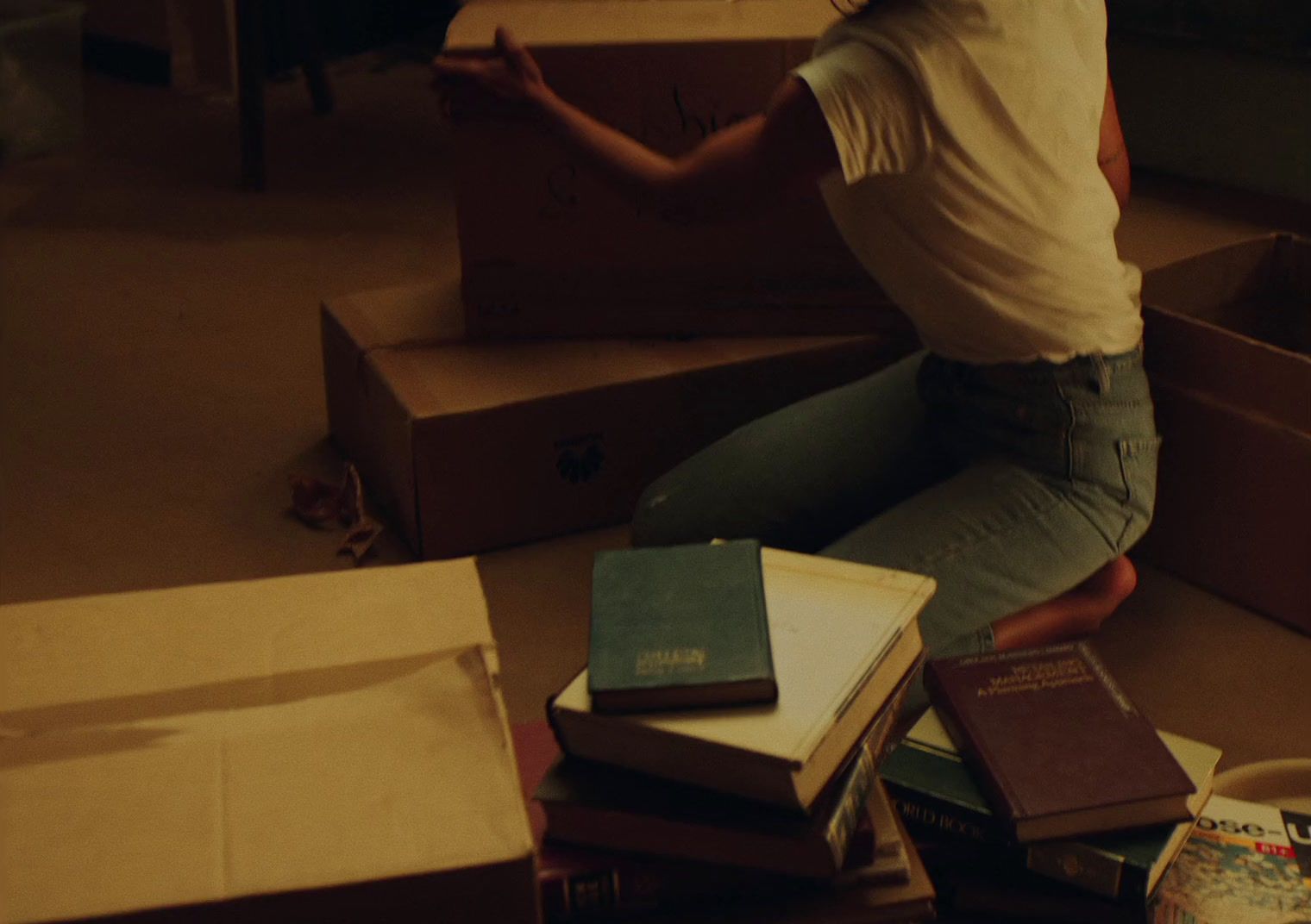 a woman sitting on the floor surrounded by boxes of books