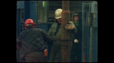 a group of men standing around a wooden pole