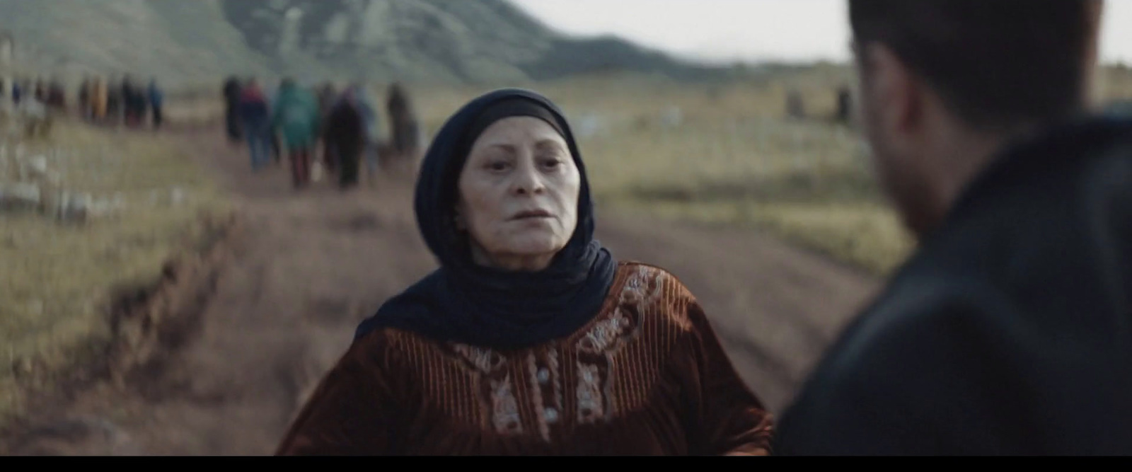 a woman in a headscarf walking down a dirt road