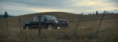 a black truck parked in a field behind a fence