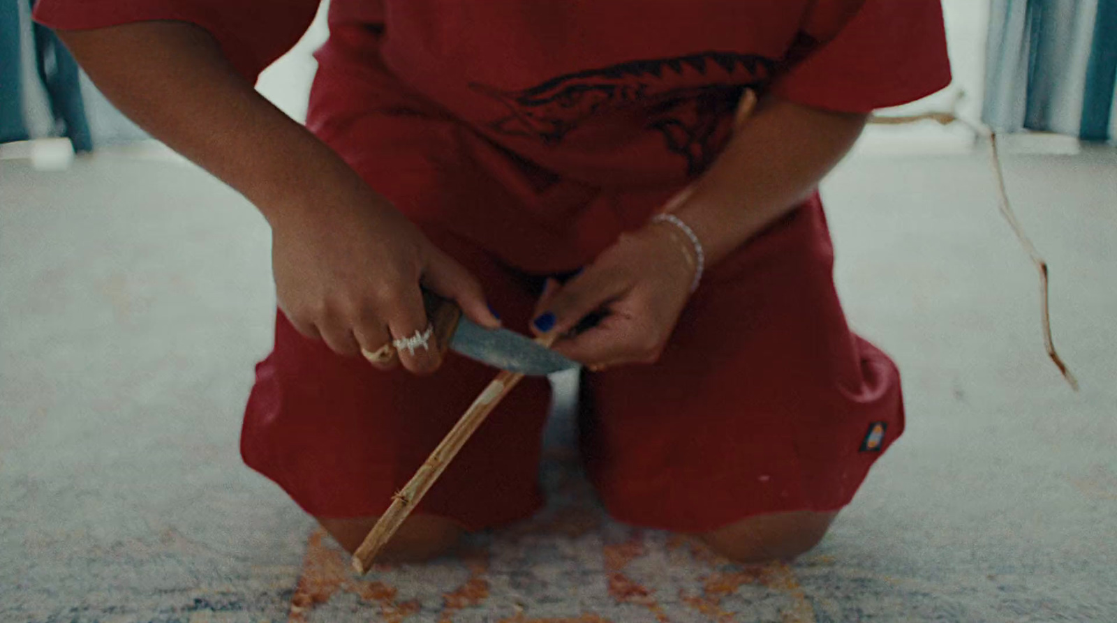 a person sitting on the floor with a knife in their hand