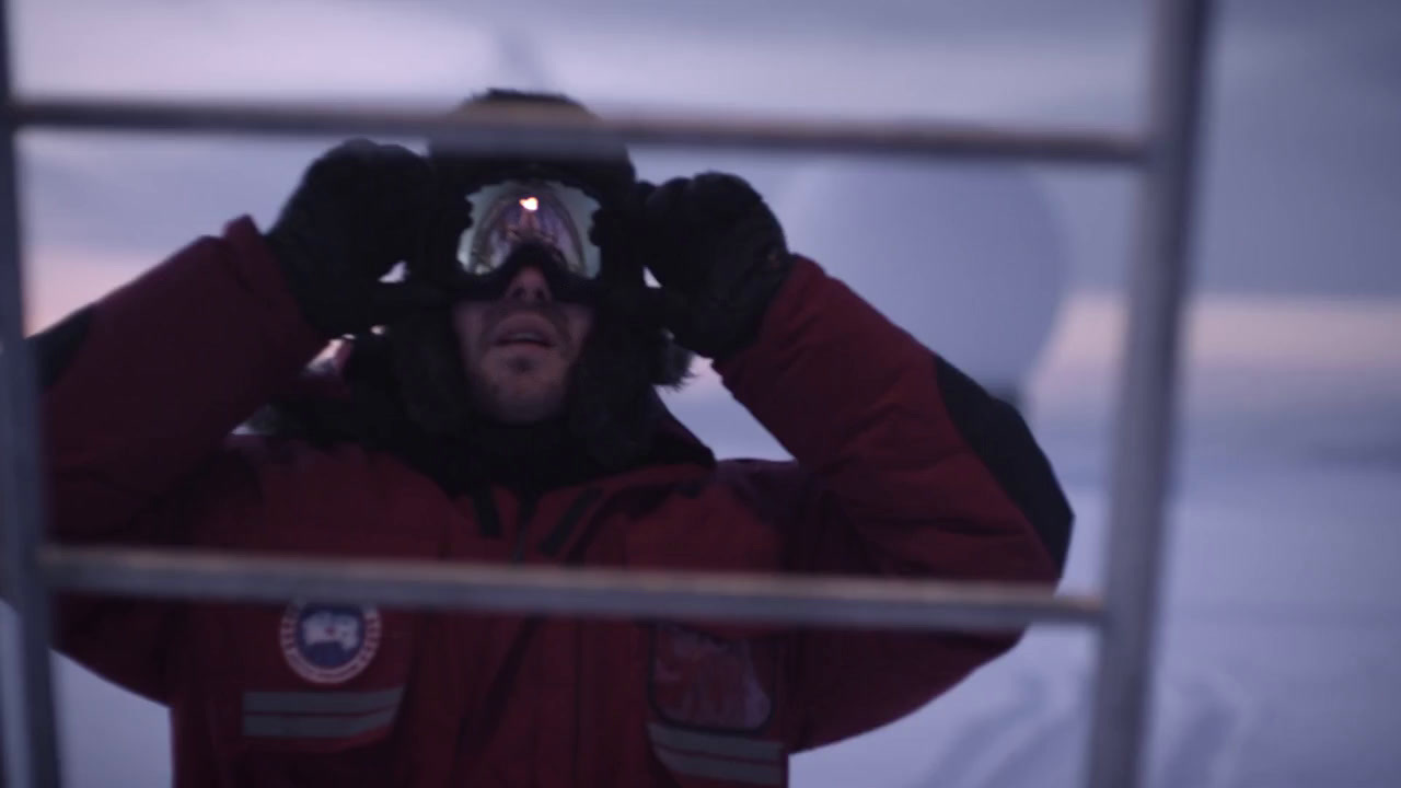 a man in a red jacket looking through a window