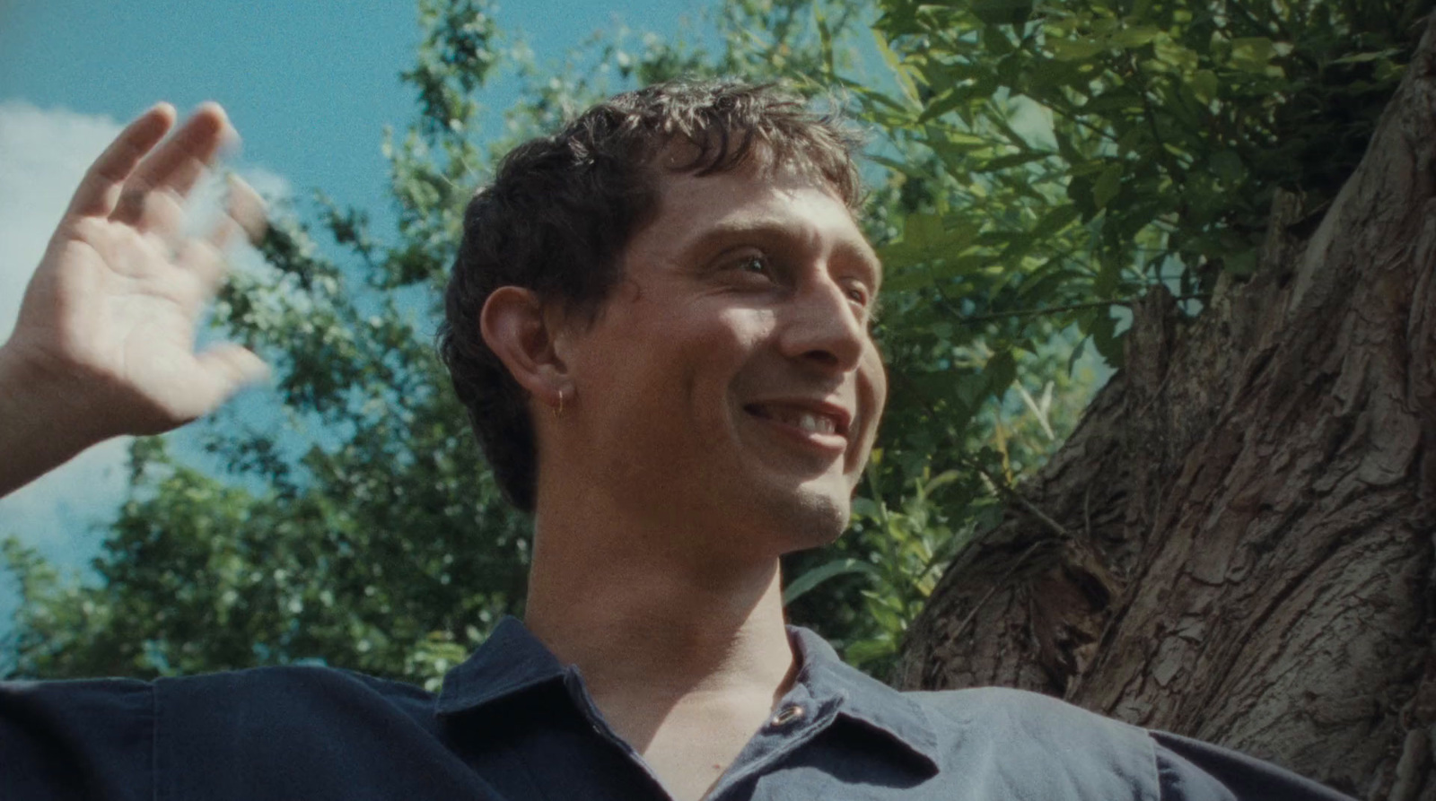 a man standing in front of a tree waving