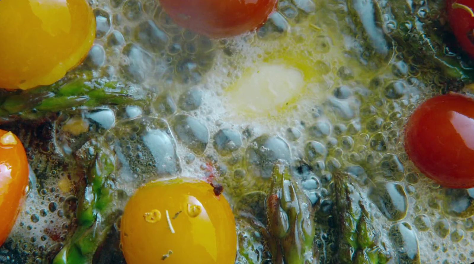 a close up of tomatoes and asparagus in oil