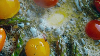 a close up of tomatoes and asparagus in oil