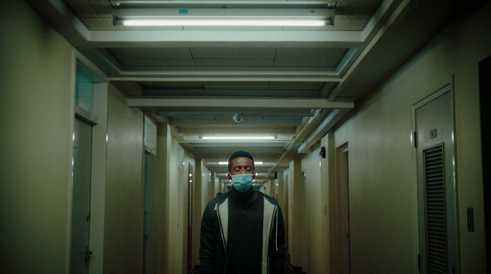 a man wearing a face mask walking down a hallway