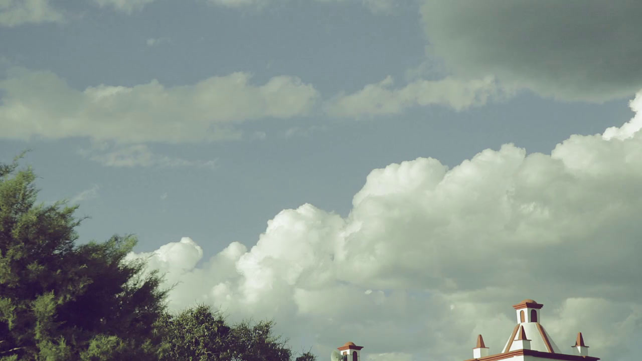 a clock tower on a cloudy day with trees in the foreground