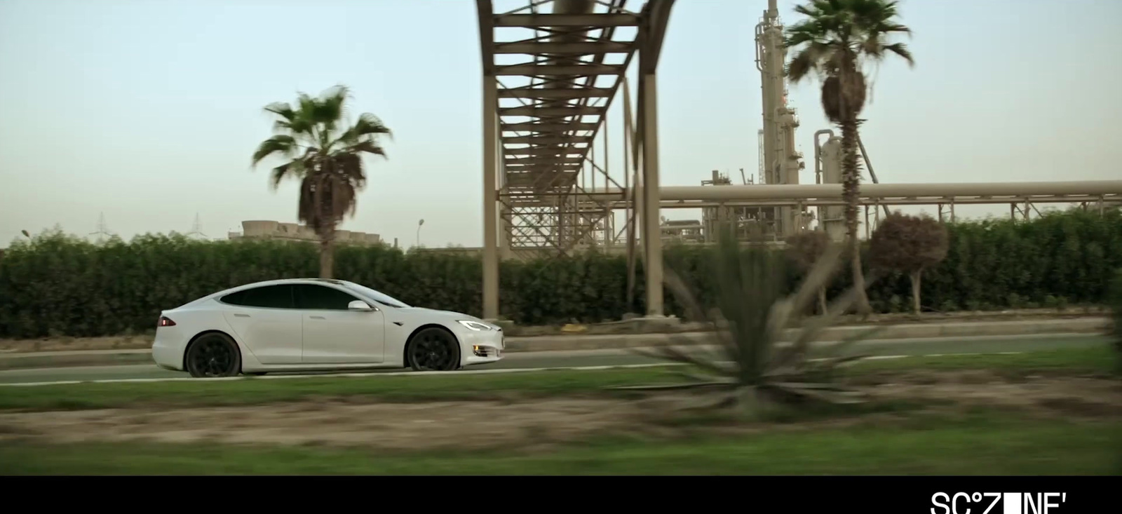 a white car driving down a road next to palm trees