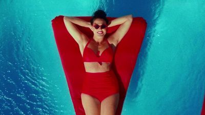 a woman in a red bikini laying on a red raft