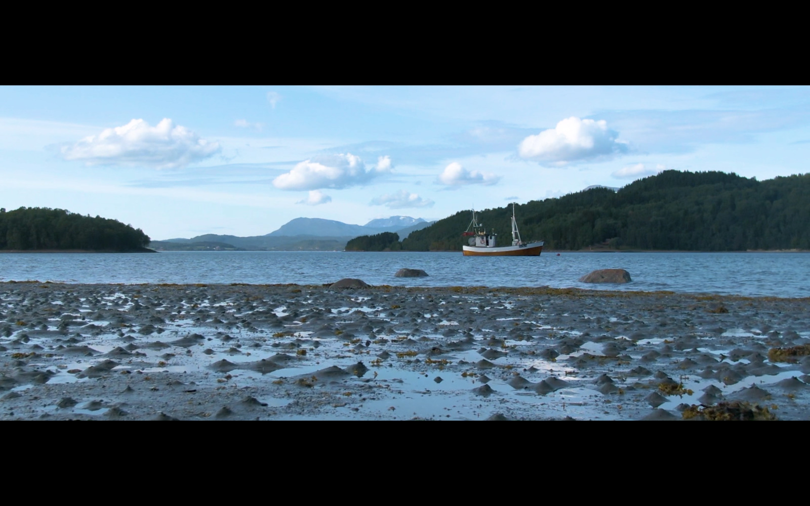 a boat on the water near a rocky shore