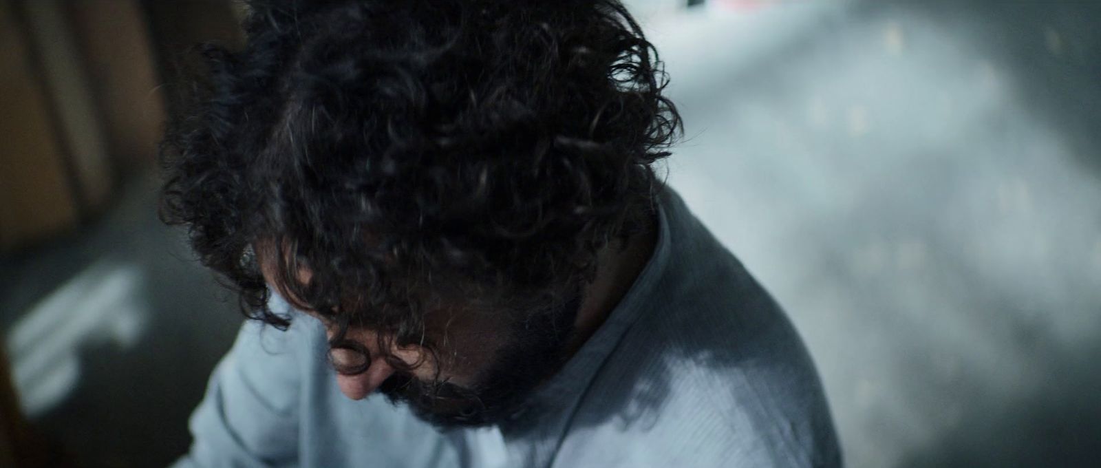 a man with curly hair looking down at something