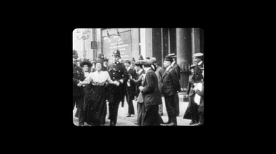 a group of people walking down a street next to tall buildings