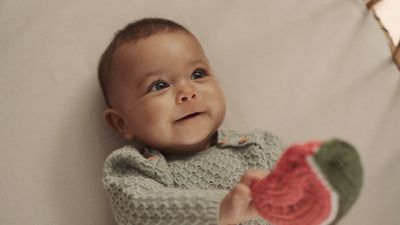 a baby is smiling while holding a piece of crochet