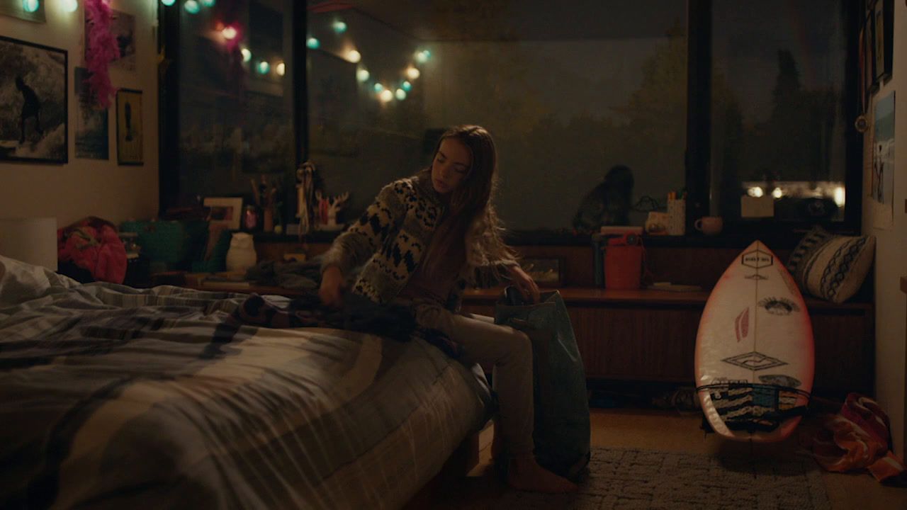 a person sitting on a bed with a surfboard