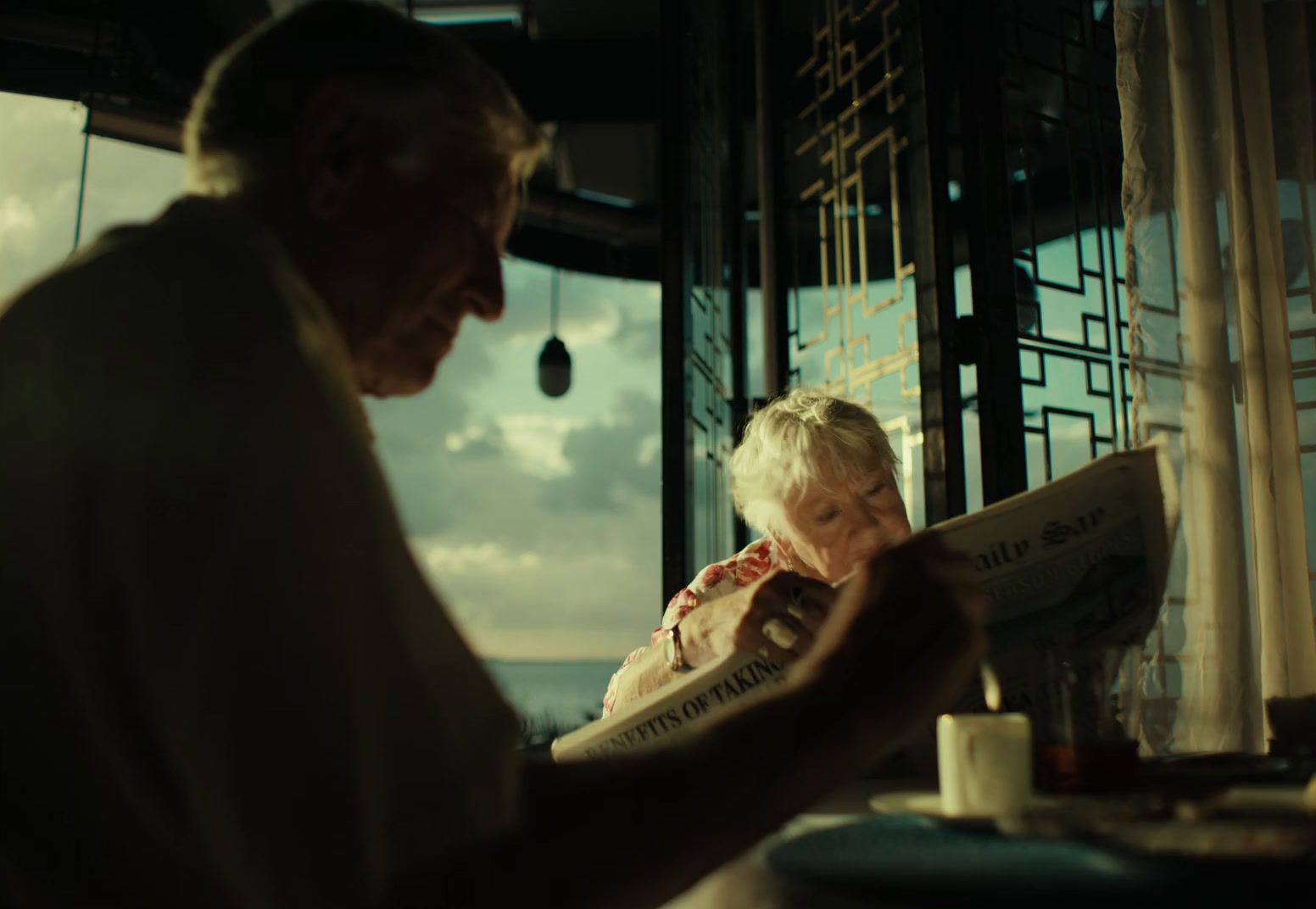 a man and a woman sitting at a table reading a newspaper