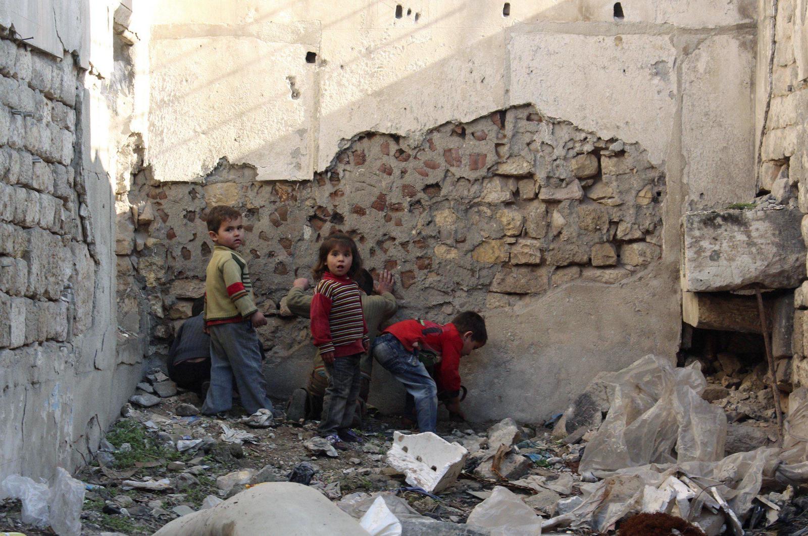 a group of young boys standing next to a pile of rubble