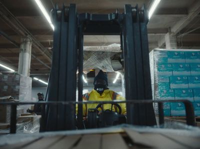 a man in a yellow jacket is driving a forklift