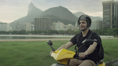 a man riding a yellow scooter in a city park