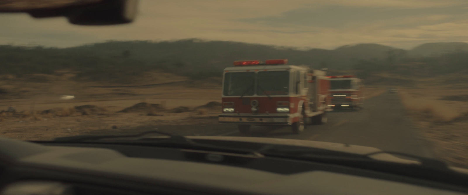 a couple of fire trucks driving down a road