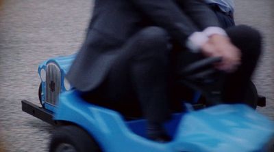 a man in a suit riding a toy car