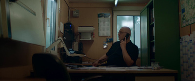 a man sitting at a desk talking on a cell phone