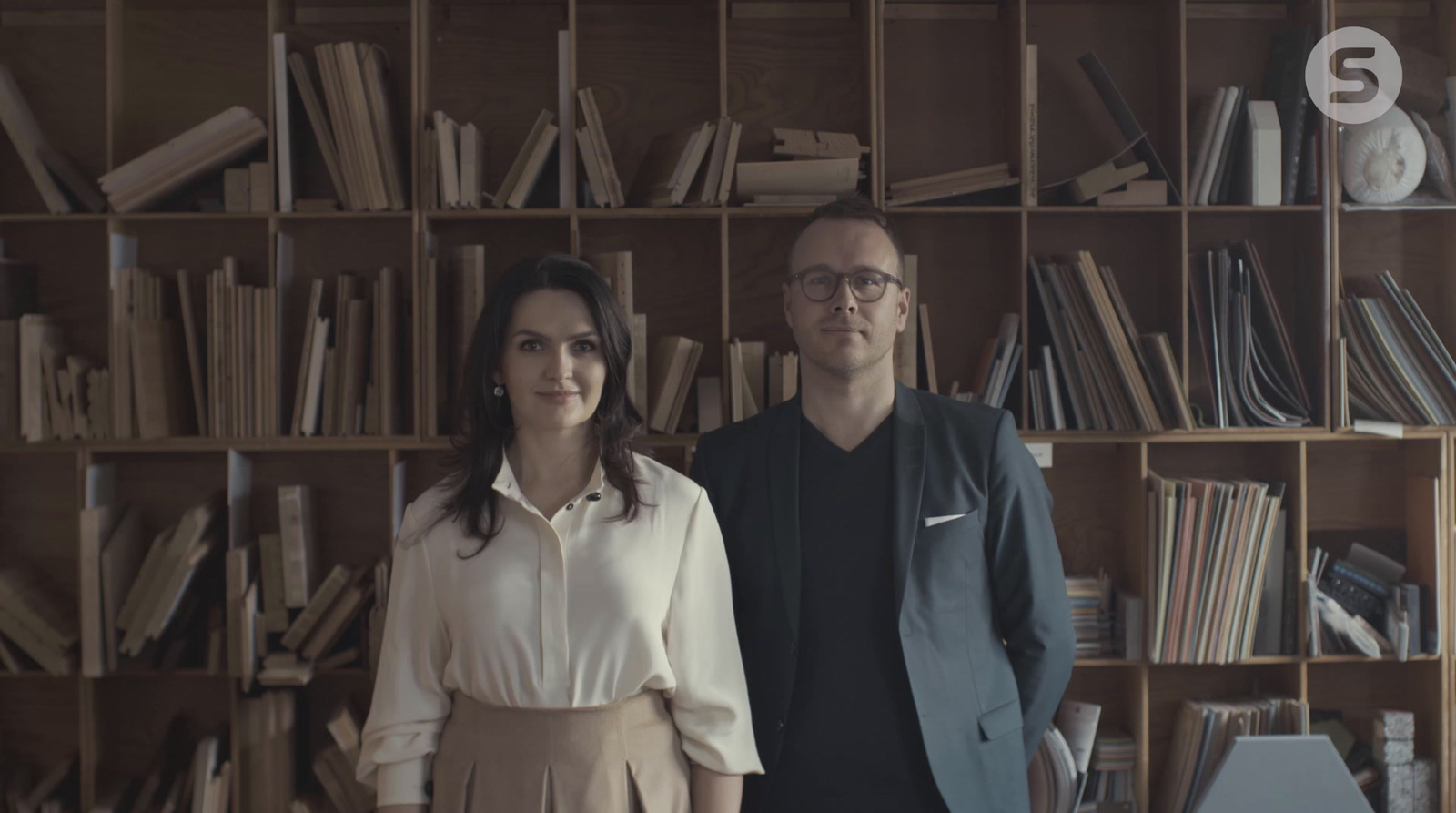 a man and a woman standing in front of a bookshelf