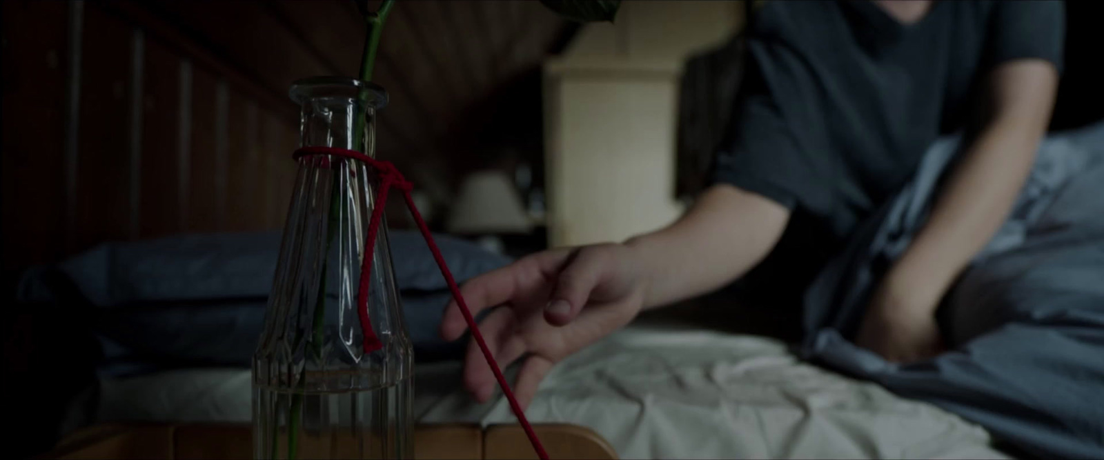 a person sitting on a bed with a flower in a vase