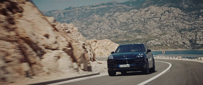 a black porsche cayen driving down a mountain road