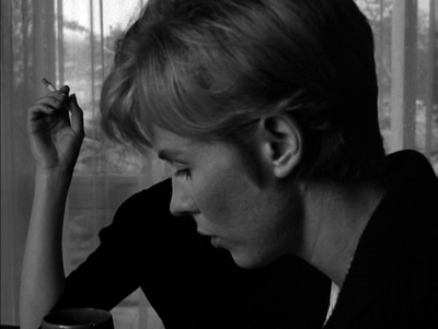 a woman sitting at a table smoking a cigarette