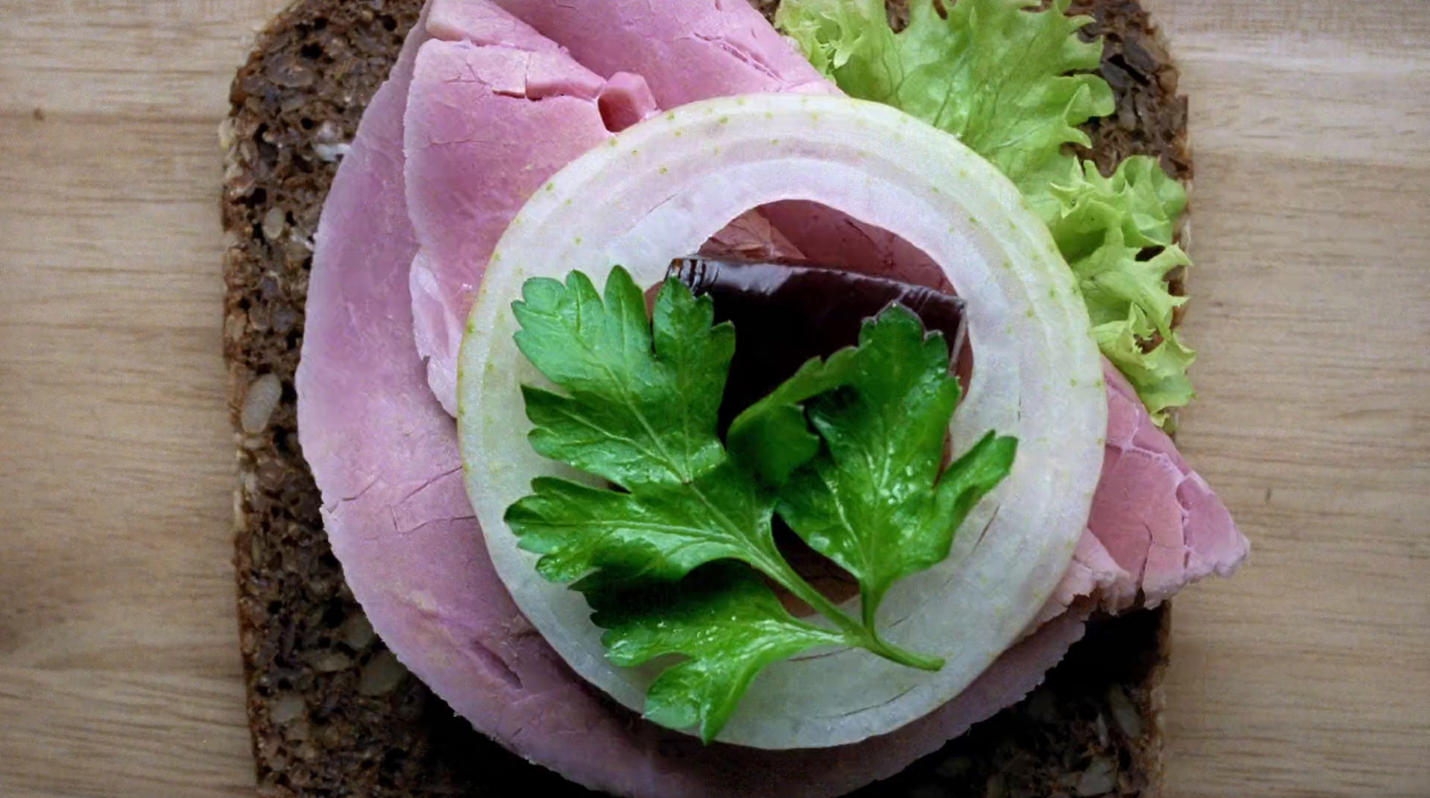 a sandwich with meat and lettuce on a wooden surface