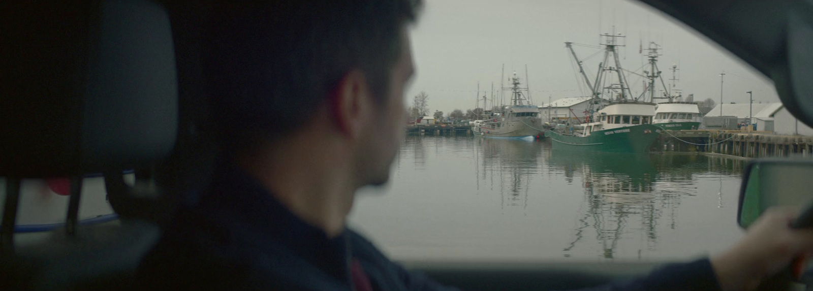 a man driving a car in front of a marina