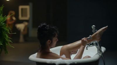 a woman sitting in a bathtub with a plant in the background