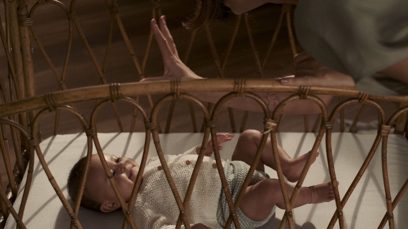 a baby laying in a crib next to a woman