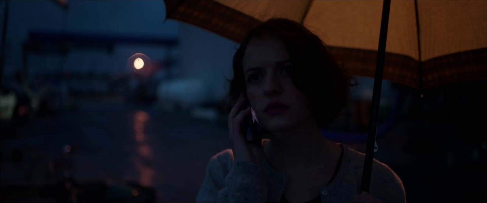 a woman talking on a cell phone under an umbrella