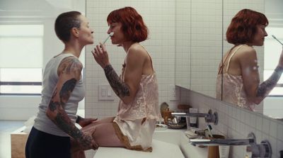 a man and a woman sitting in front of a bathroom mirror