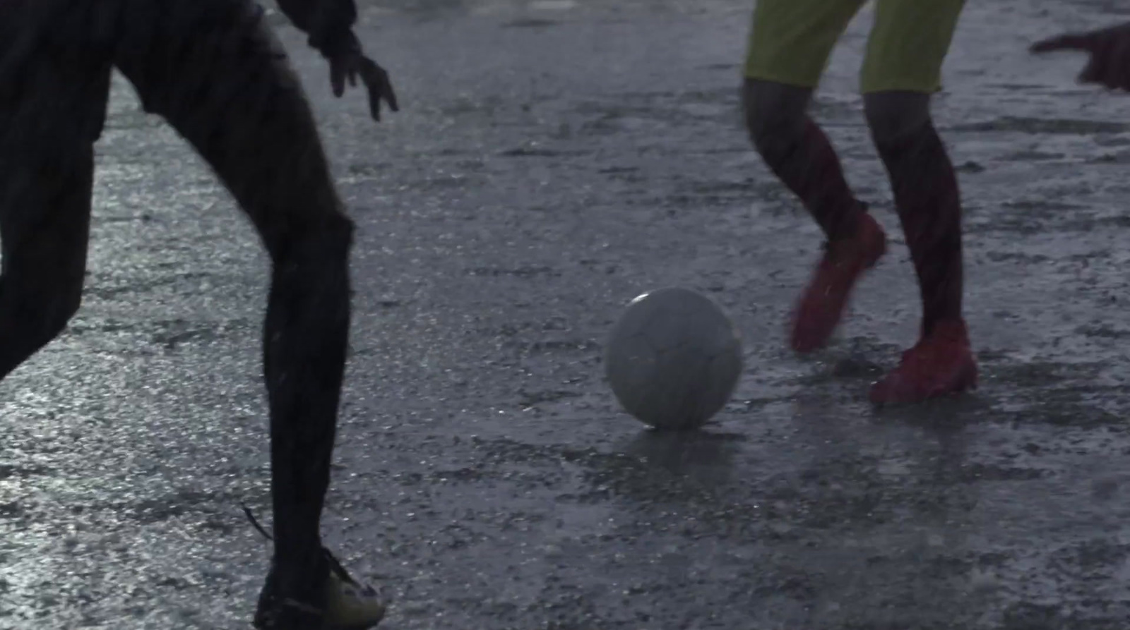 a couple of people playing with a ball in the rain