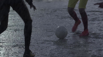 a couple of people playing with a ball in the rain