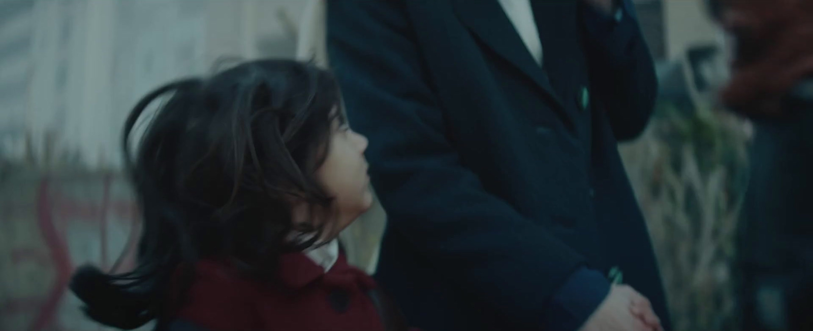 a little girl holding the hand of a man in a suit