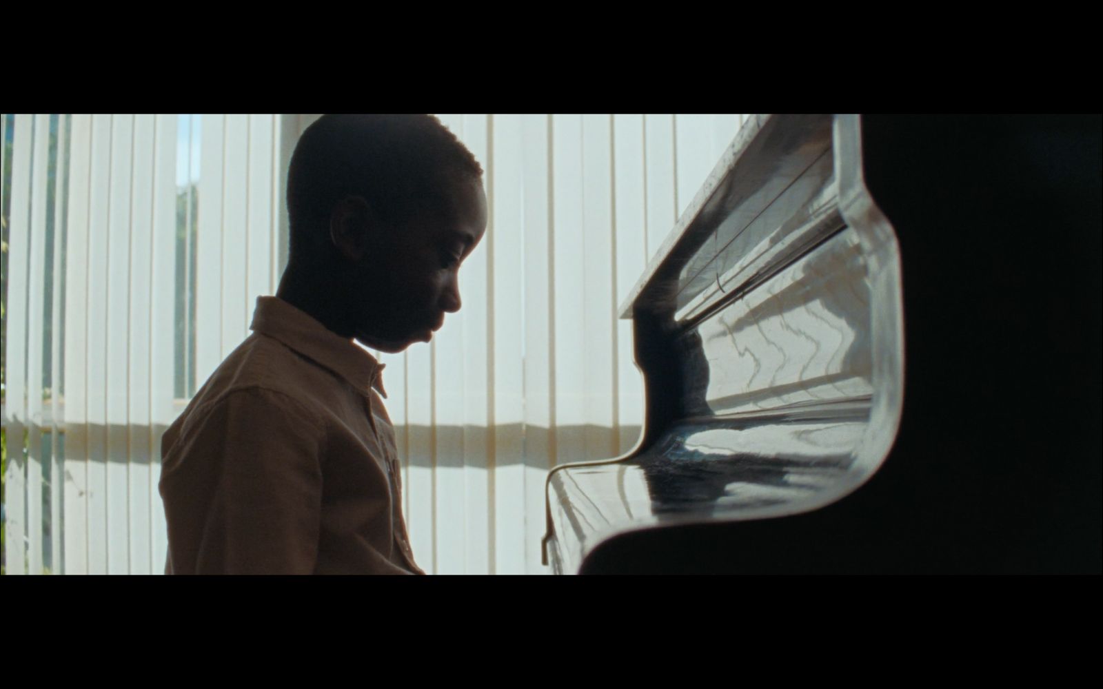 a man standing next to a piano in front of a window