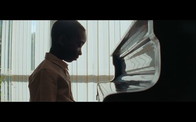 a man standing next to a piano in front of a window