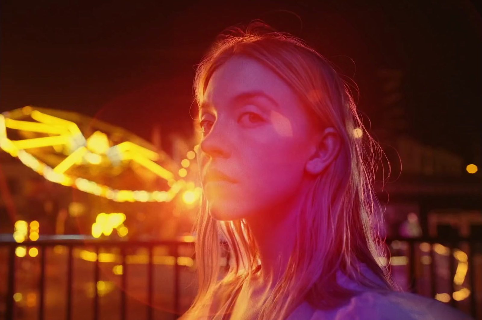 a woman standing in front of a carnival ride at night