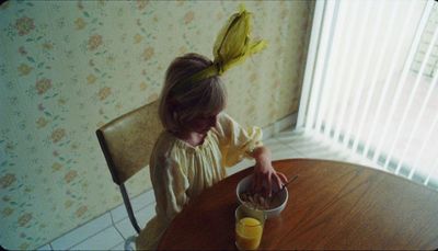 a little girl sitting at a table with a bowl of food