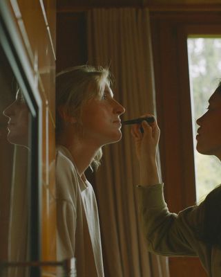 a woman putting lipstick on another woman's face