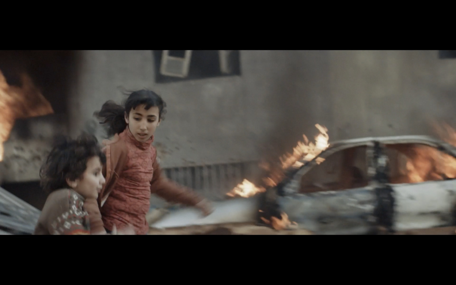 a couple of kids that are standing in front of a fire